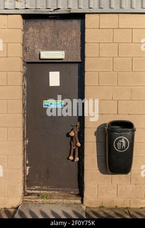 Bristol-March 2021, England-A close up view of a closed door with a monkey toy hanging off the door handle