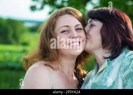 Mom kisses her daughter. Smiling dad carries his daughter on his