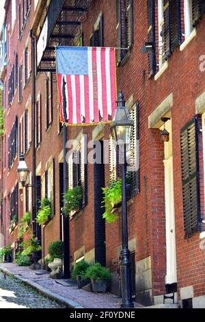 Betsy Ross flag hangs over the colonial house fronts along Acorn St. in Boston with brick and streetlight features. Stock Photo