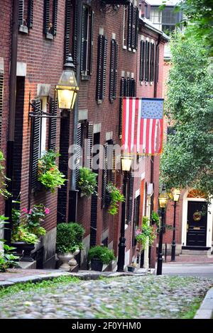 Betsy Ross flag hangs over the colonial house fronts along Acorn St. in Boston with brick and streelight features. at dawn. Stock Photo