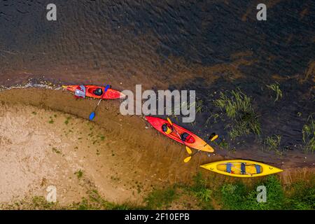multicolored empty kayaks and canoes on the river bank, top down view Stock Photo