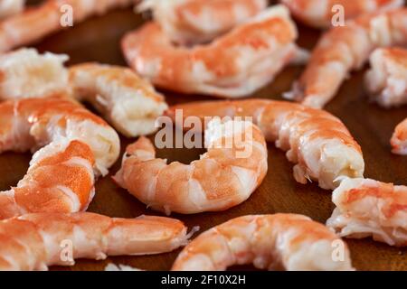 Closeup of unshelled fresh red prawns on a wooden board Stock Photo