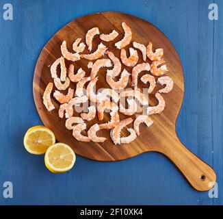 Unshelled raw red prawns on wooden board Stock Photo