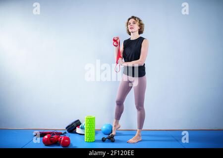 Sportswoman performs exercises with resistance band. People, sport and fitness. Young woman training with workout band in gym. Active lifestyle Stock Photo