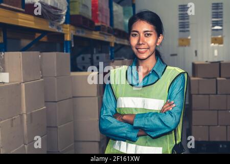 Portrait of young woman warehouse worker smiling in the storehouse . Logistics , supply chain and warehouse business concept . Stock Photo