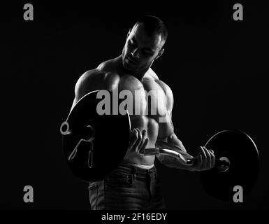 Muscular strong men, athlete, bodybuilder, weightlifter does exercises, working out with barbell. Side view Stock Photo