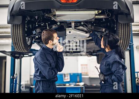 Auto car repair service center. Two mechanics - man and woman examining car Stock Photo