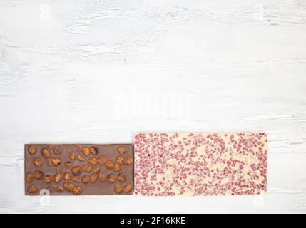 a lot of different sweet, delicate chocolate bars lie creatively on a white wooden background Stock Photo