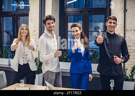 businesspeople showing thumbs up in office Stock Photo