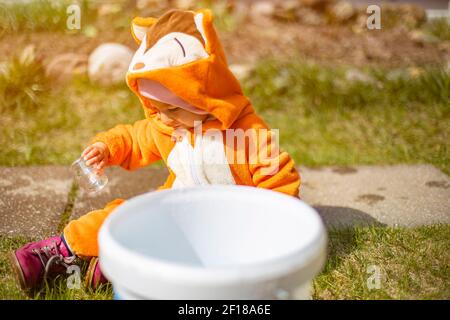 adorable toddler plays with water and tap in the sunshine Stock Photo