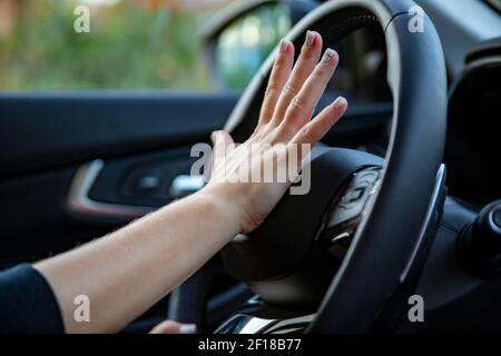 female hand presses the horn on the steering wheel of a modern car. no face Stock Photo