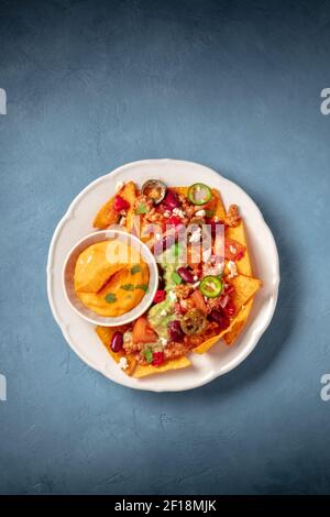 Nachos with ground beef, guacamole and cheese dip, shot from above on a blue background Stock Photo
