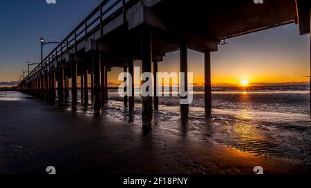 Sun Setting over the Horizon and Canada's Longest Pier in Semiahmoo Bay at the village of White Rock in British Columbia, Canada Stock Photo