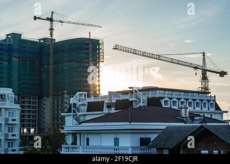 Modern big multi-storey residential or office high rise building under construction, sunrise sky background, tower cranes. Real estate business Stock Photo