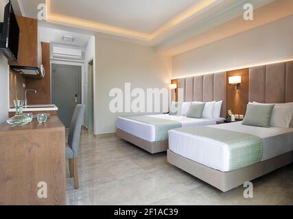 Modern apartment interior of bedroom with oak wood furniture, single, double king size bed, soft grey textile headboard. Contemporary family studio ho Stock Photo