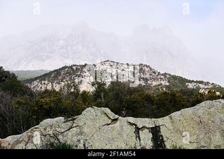 mountain range in the clouds is barely visible behind the rocks on the foreground Stock Photo