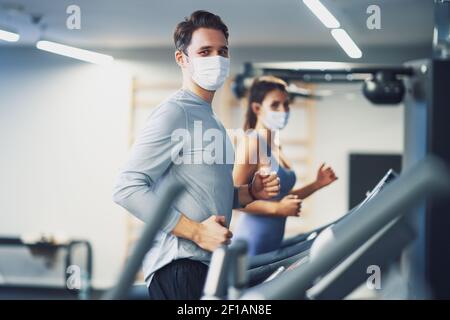 Two people working out on treadmill in masks Stock Photo