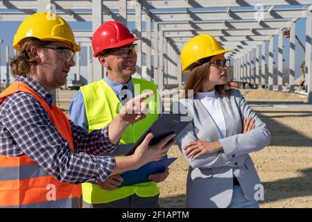Portrait of Foreman with Digital Tablet, Manager and Young Female Architect at Construction Site. Business Relationship and Teamwork Concept. Stock Photo