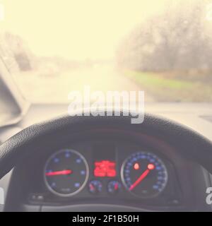 View from the driver - car interior with steering wheel and dashboard. Winter bad rainy weather and dangerous driving on the road. Stock Photo