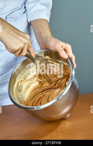 Chef whips yellow cream in a bowl by hand for making cheesecakes Stock Photo