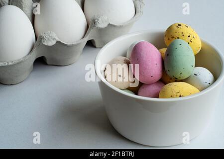 Chocolate Easter eggs in various colors in a bowl. In the background is a egg carton. Stock Photo