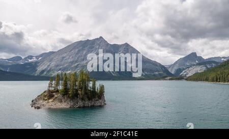 Isolated island on alpine lake with mountains in backdrop. Shot at Upper Kananaskis Lake trail, Alberta, Canada Stock Photo