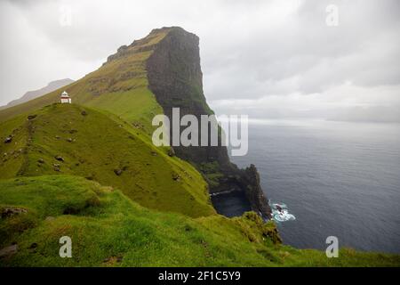 beautiful dramatic landscape in the Faroe Islands. cloudy sky, lighthouse, grass Stock Photo