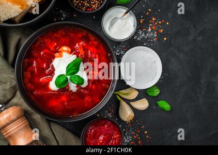 Ukrainian traditional borscht with sour cream and garlic on a black background close-up. Top view with copy space. Stock Photo