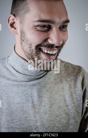 Portrait of a young man with a short beard that laughs cheerfully during a conversation Stock Photo