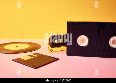Vinyl disc, floppy diskette, vhs and tape cassete on yellow background. Vintage, retro and nostalgia concept Stock Photo