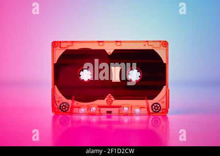 Retro cassette tape on colorful neon background, front view Stock Photo