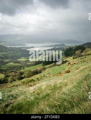 Storm approaching a valley with green rolling hills, portrait shot made on Banks Peninsula near Christchurch, New Zealand Stock Photo