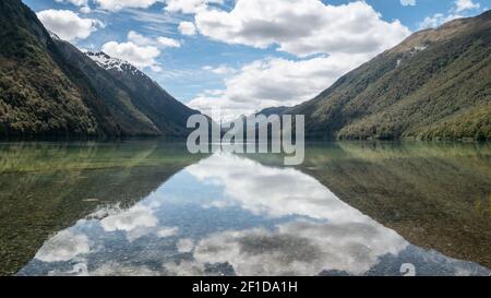 Beautiful still reflections on a lake during sunny day. Symmetric photo taken at lake Gunn, Fiordland National Park, New Zealand Stock Photo