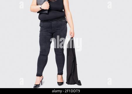 Cropped photo of overweight female legs. Plus size model girl wearing formal suit and black shoes standing isolated gray background. XXL model woman Stock Photo