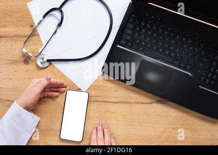Cropped shot top view of doctor hands using smartphone mockup on medical office desk. Blank screen mobile phone for graphic display montage near Stock Photo