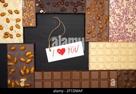 different sweet bars of chocolate lie on a black wooden background with a label that says I love you Stock Photo