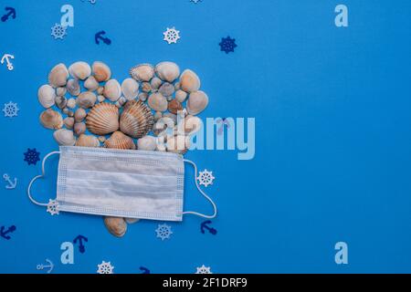 Seashells in the shape of a heart and a medical mask. Marine symbols. On a blue background. inscription. Flat lay Stock Photo