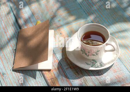 Cup of tea with notepad and yellow pen on rustic wood table. Stock Photo