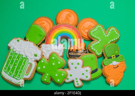 Top view of freshly baked St. Patricks Day decorated sugar cookies on green background. Homemade cookies with shamrock, rainbow, leprechaun and pot of Stock Photo