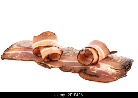 Slicing dry-cured pork brisket isolated on white background. Two pieces rolled up. Close up. Copy space. Stock Photo