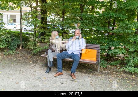 Woman sitting on a bench getting angry because a man not caring about social distancing during coronavirus times Stock Photo