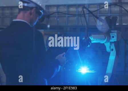 Manager engineer check and control automation robot arms machine in intelligent factory industrial on real time monitoring system software. Welding ro Stock Photo