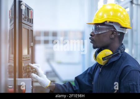 Black man working at programmable machine in factory industries Stock Photo