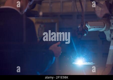 Manager engineer check and control automation robot arms machine in intelligent factory industrial on real time monitoring system software. Welding ro Stock Photo