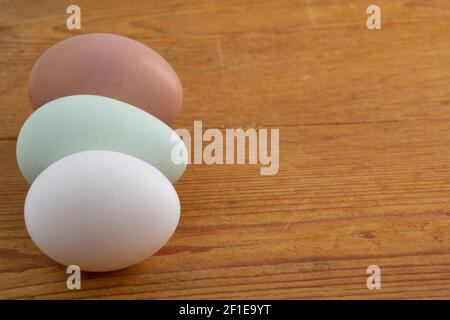 White, brown and green Araucana chicken egg laying on a wooden cutting board with copy space Stock Photo