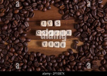 Beans Coffee all around on a wooden table. it's coffee time with a wooden cube letters. aroma of fresh coffee. Stock Photo