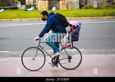 A father and young daughter riding bicycles on the street. We see them in profile, in action. Family routine, family, lifestyle, green transport. Stock Photo