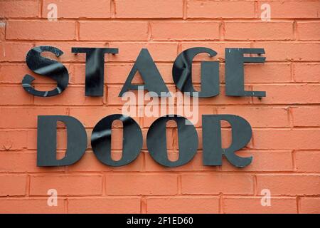Stage Door black lettering on bright orange brick wall Stock Photo