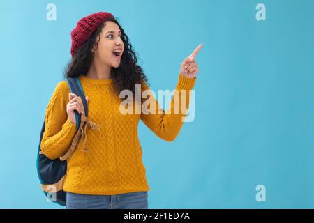 A TEENAGER STANDING WITH BAG POINTING ABOVE IN SURPRISE Stock Photo