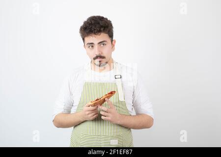 Image of male cook with slice of pizza looking at camera on white background Stock Photo
